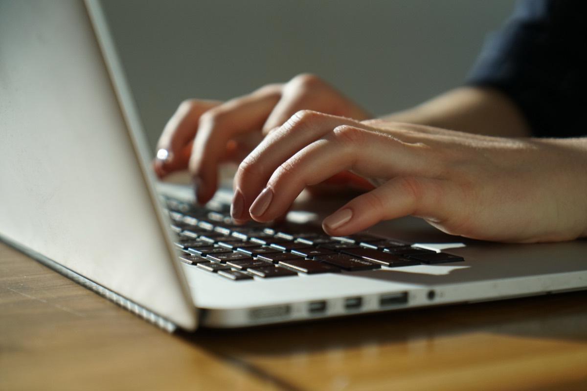 Hands typing on a laptop keyboard